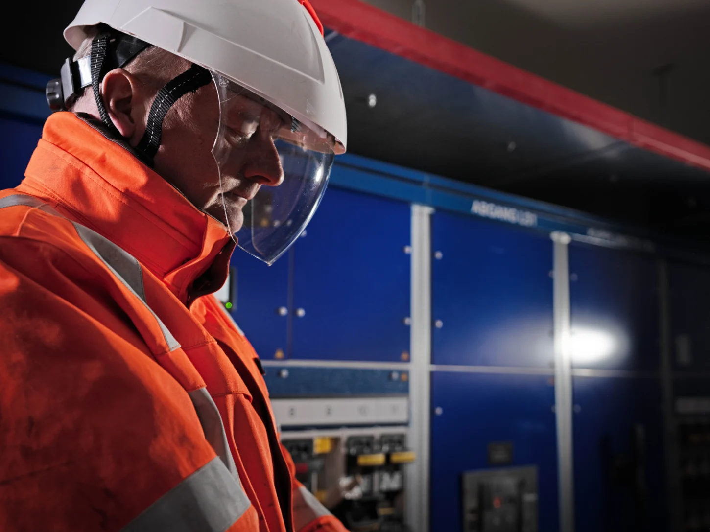 Daniel Spring überprüft eine Schaltanlage in einer Trafostation mit Schutzhelm und Visier